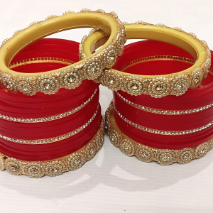 Red bridal chura set with pearl-studded golden kada and rhinestone detailing.