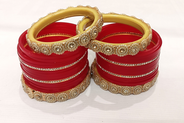 Red bridal chura set with pearl-studded golden kada and rhinestone detailing.