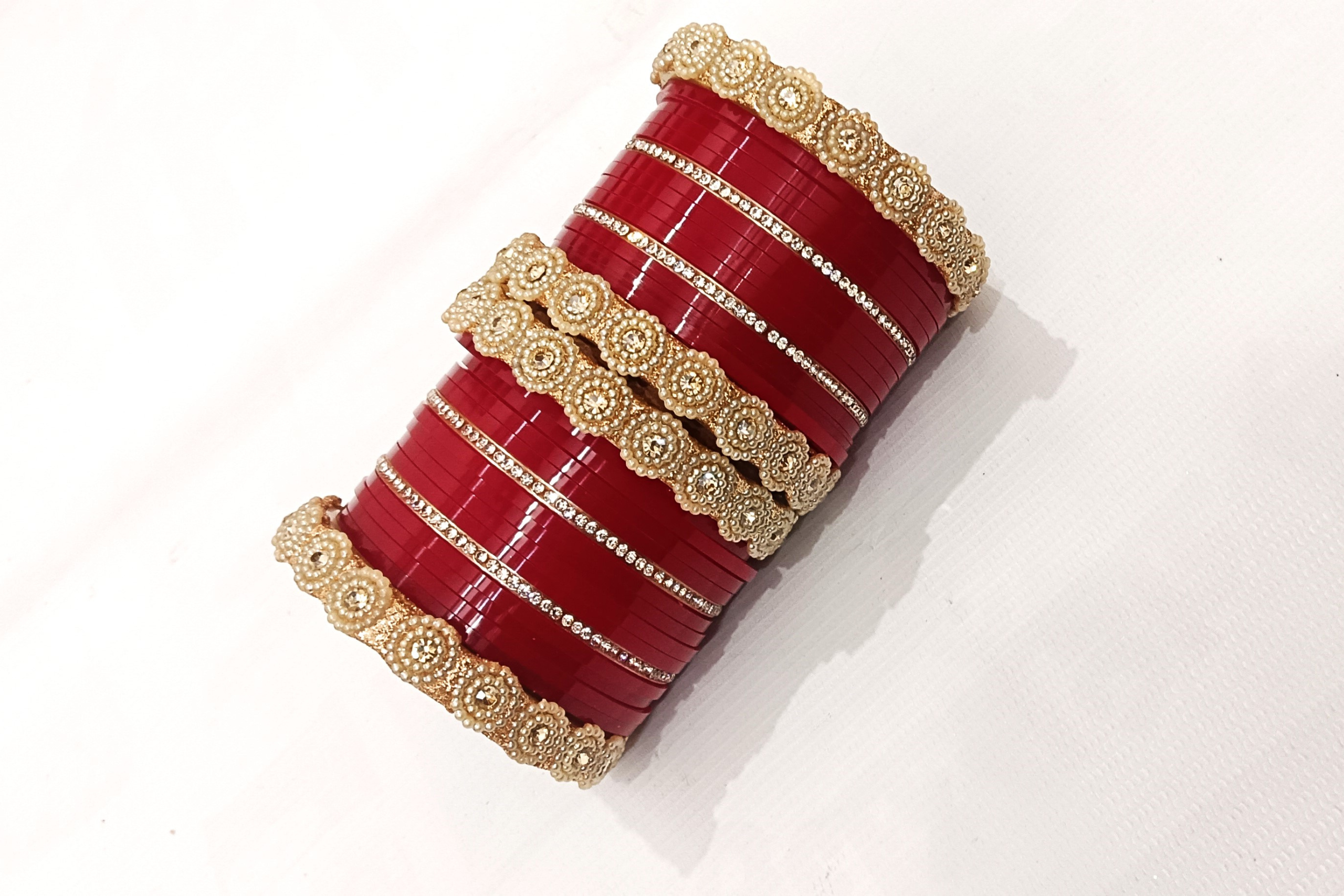 Red bridal chura set with pearl-studded golden kada and rhinestone detailing. - Image 2